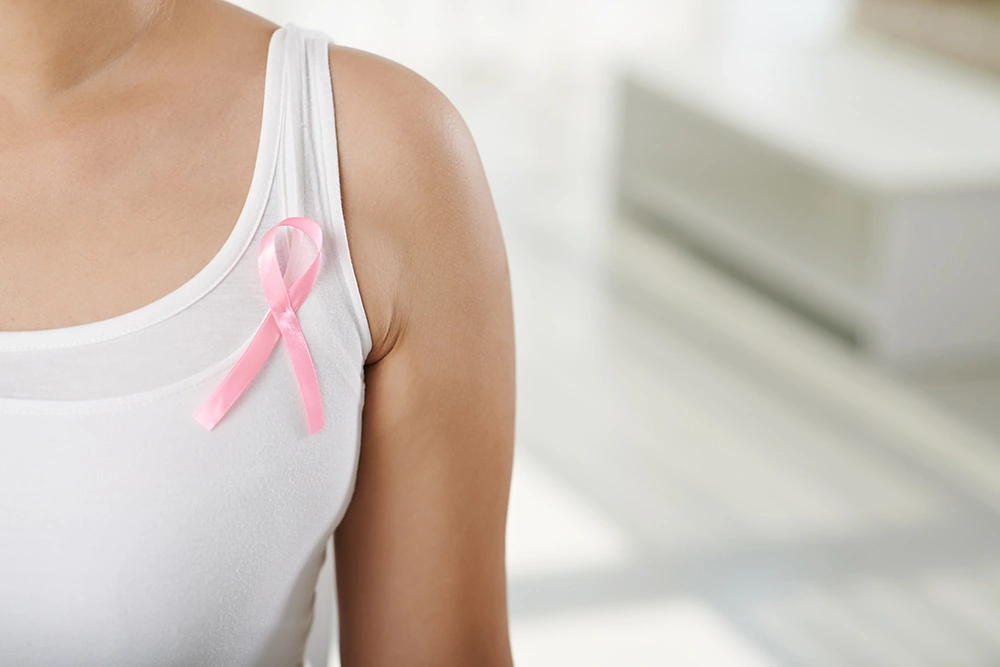 A close-up of a woman wearing a pink ribbon representing breast cancer awareness