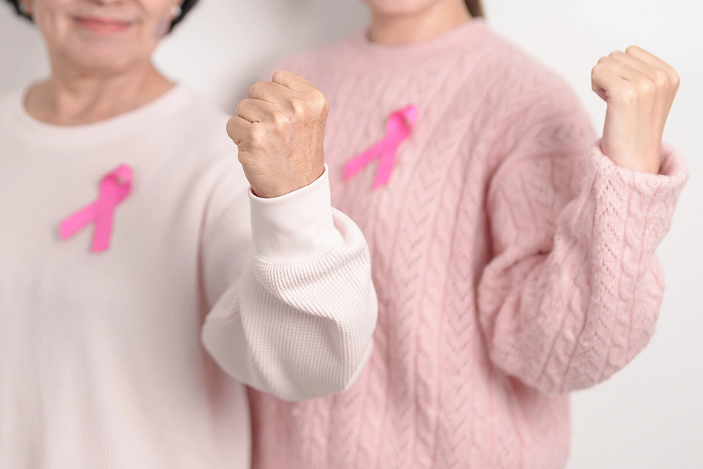 Two women wearing pink ribbons for breast cancer awareness